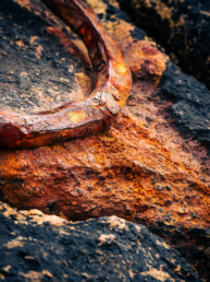 Photographie d'un anneau rouillé servant à amarrer les bateaux. L'anneau a été scellé dans la pierre, une roche de granit sur la place de Rospico en Bretagne dans le Finistère. Le tirage d'art est numéroté et en série limité. Il fait partie de l'exposition Ondes Marines de Cécile Hoynant