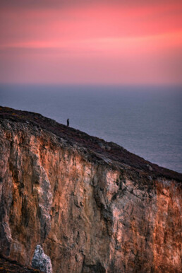 Photo d'art, tirage numéroté et signé en série limitée, silhouette contemplant un sublime coucher du soleil du haut d'une falaise de la presqu'île de Crozon, au Cap de la Chèvre, Bretagne.