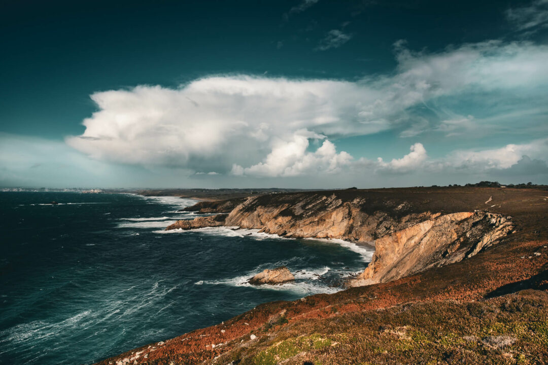 Vue sur la presqu'île de Crozon depuis le sentier côtier. Paysage de mer grandiose avec les hautes falaises surplombant la mer. Nuage d'orage cumulonimbus après le passage de la tempête Ciaran. La végétation typique de landes a pris ses couleurs d’automne.