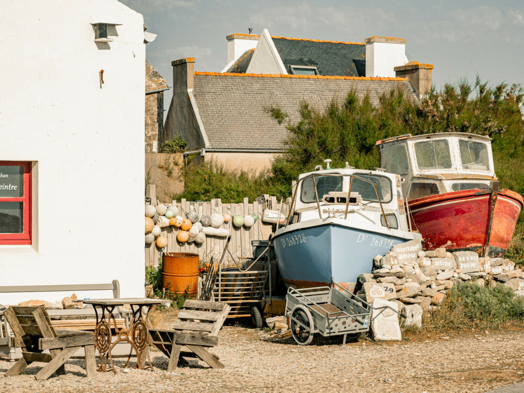 Jardin d'artiste à l'île de Sein dans le Finistère en Bretagne. Coques de bateau dans un jardin avec des bouées de pêcheur sur le palissade. Jardin d'extérieur.