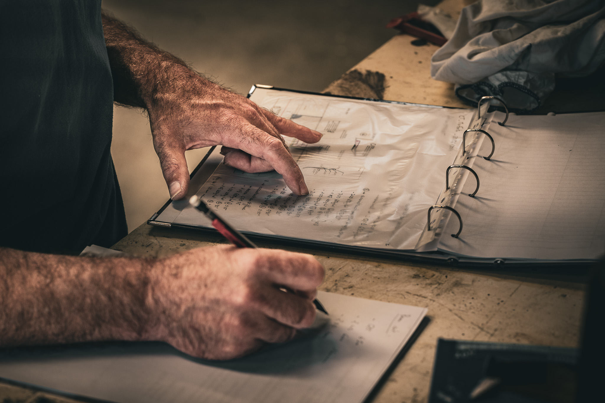 détail sur les mains d'un technicien d'un chantier nautique prenant des notes pour la fabrication d'une pièce en composite de Figaro 3